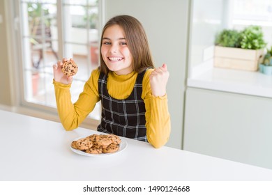 Beautiful Young Girl Kid Eating Chocolate Chips Cookies Screaming Proud And Celebrating Victory And Success Very Excited, Cheering Emotion