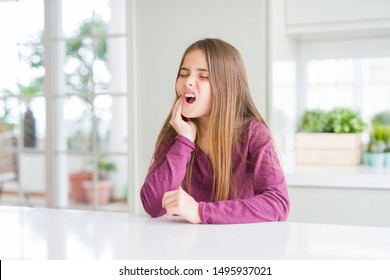 Beautiful Young Girl Kid On White Table Touching Mouth With Hand With Painful Expression Because Of Toothache Or Dental Illness On Teeth. Dentist Concept.