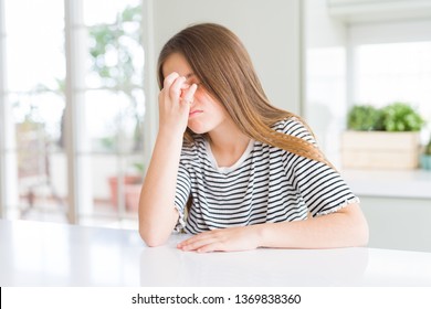 Beautiful young girl kid wearing stripes t-shirt tired rubbing nose and eyes feeling fatigue and headache. Stress and frustration concept.