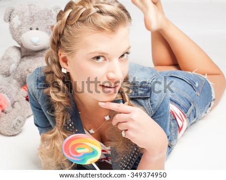 beautiful young girl with lollipop and teddy bear  on the floor