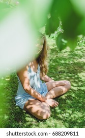 Beautiful young girl with long blond hair meditating in the garden, in a park under the trees - Shutterstock ID 688209811