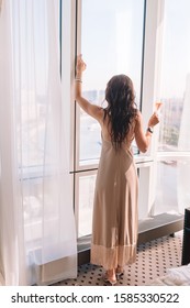 Beautiful young girl in long dress in hotel on the party with view on the city - Shutterstock ID 1585330522