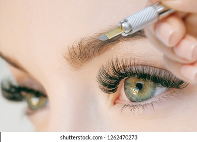 Beautiful young girl with long eyelashes tweezing her eyebrows in a beauty salon. Eyebrow Correction. Beauty Concept. Permanent Makeup. Microblading brow. Beautician Doing brows Tattooing. Treatment.