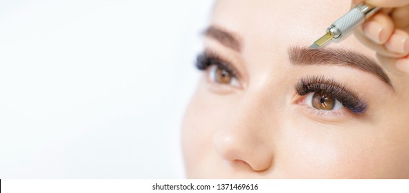 Beautiful Young Girl With Long Eyelashes Tweezing Her Eyebrows In A Beauty Salon. Woman Doing Eyebrow Permanent Makeup Correction . Microblading Brow.