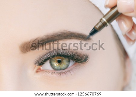 Beautiful young girl with long eyelashes tweezing her eyebrows in a beauty salon. Eyebrow Correction. Beauty Concept. Permanent Makeup. Microblading brow. Beautician Doing brows Tattooing. Treatment.