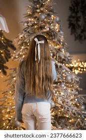 Beautiful young girl with long hair near the Christmas tree. Christmas holidays at home
