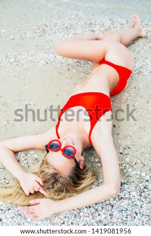 A beautiful young girl with long hair in a red swimsuit  relax on beach in the sea in sunny hot day