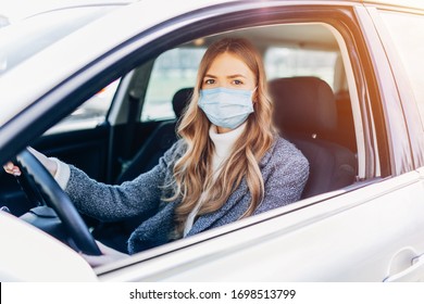 Beautiful young girl in a mask sitting in a car, protective mask against coronavirus, driver on a city street during a coronavirus outbreak, covid-19