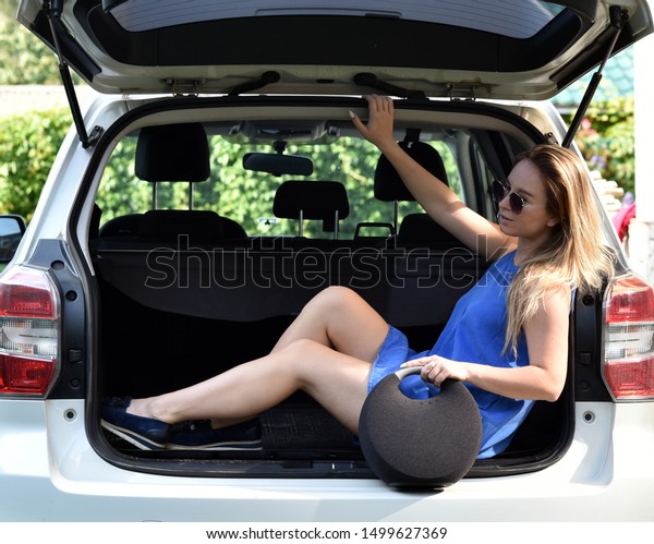 Beautiful young girl with a music column near the\
car. Music in the car