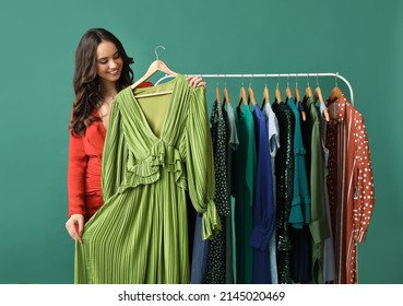 Beautiful Young Girl Near Rack With Clothes For High School Prom On Green Background