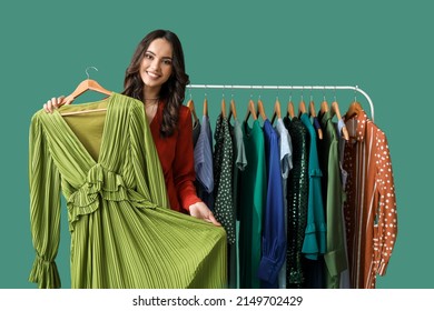 Beautiful Young Girl Near Rack With Clothes For High School Prom On Green Background