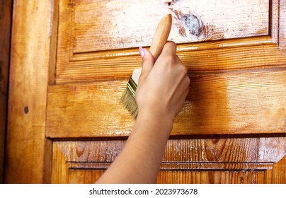 Beautiful young girl paints a wooden door. Summer work in the garden. Selective focus - Powered by Shutterstock