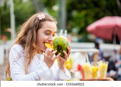 Beautiful young girl at Paseo Bolivar Square in the city of Cali eating tropical fruits in Colombia