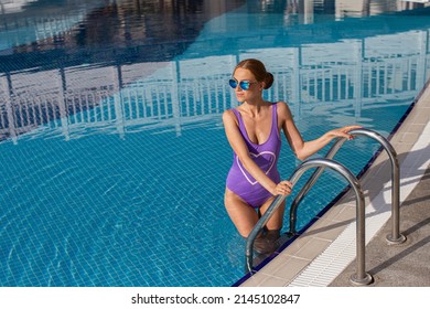 Beautiful young girl with perfect slim figure with long wet hair and bathing suit in fashionable stylish sun glasses sitting on the steps of swimming pool swim, sunbathe, have fun at beach party