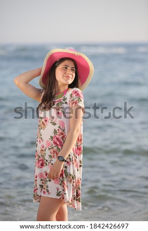 Beautiful young girl with a pink straw hat on a tropical beach