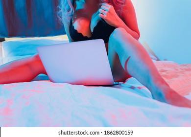 Beautiful, young girl posing in front of a web camera, working as a sexual model. The concept of online flirting, sex on the Internet.