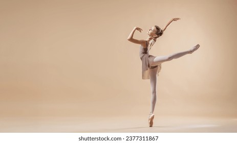 Beautiful young girl professional student ballerina in pointe shoes and a leotard on light beige background. - Powered by Shutterstock