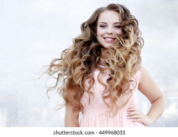 Beautiful Young Girl At The Prom With Gorgeous Long Curly Hair . Professional Make-up And Hairstyle , Stylish Woman .