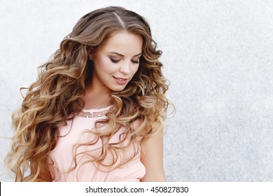 Beautiful Young Girl At The Prom With Gorgeous Long Curly Hair . Professional Make-up And Hairstyle , Stylish Woman .