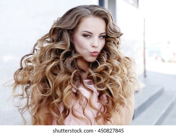 Beautiful Young Girl At The Prom With Gorgeous Long Curly Hair . Professional Make-up And Hairstyle , Stylish Woman .