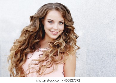 Beautiful Young Girl At The Prom With Gorgeous Long Curly Hair . Professional Make-up And Hairstyle , Stylish Woman .