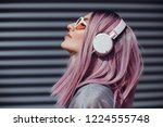 Beautiful young girl with purple pink hair listening to music on headphones, street style, outdoor portrait, hipster girl, music, mp3, Bali, beauty woman, sunglasses, orange color, concept