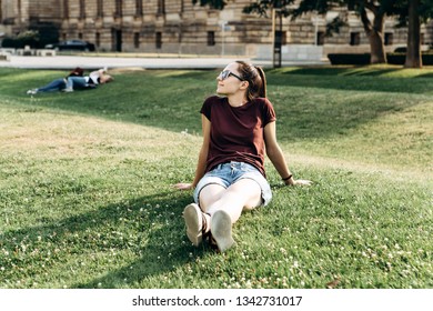 Beautiful Young Girl Resting On The Grass On The Street In Leipzig In Germany. Rest Of People In The City.