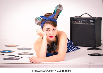 Beautiful Young Girl In Retro Clothes And Hairstyle Representing Pinup Style Lying On The Floor With Vynil Records Isolated On White