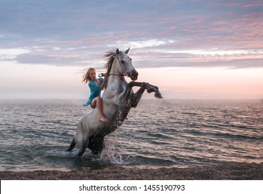 beautiful young girl riding a horse walking along the sandy beach at sunset time