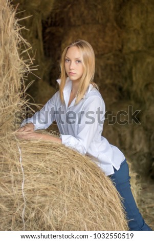 beautiful young girl with a shirt and trousers sitting in the barn. Hay store with stables