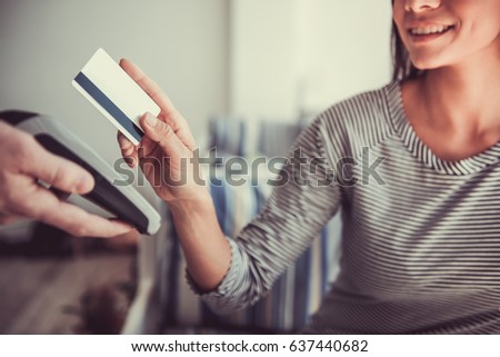 Beautiful young girl sitting in a cafe and pay with a bank card
