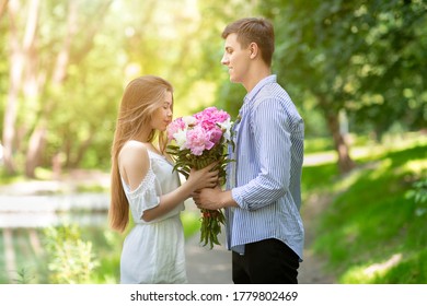 Beautiful Young Girl Smelling Bouquet Of Peonies Given By Her Boyfriend At Park