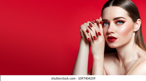 Beautiful young girl in studio on gray background. Close-up portrait. Hairstyle styling. Smooth shiny hair and skin. Red lips, red nails. fashion, beauty, makeup, cosmetics, beauty salon, style.