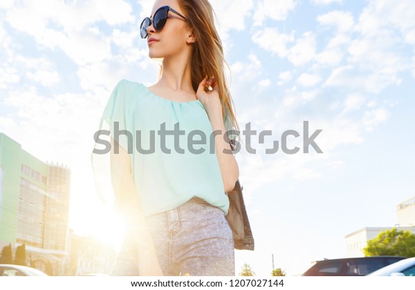 Beautiful young girl with sunglasses smiling on\
sunny street. Lifestyle\
Concept