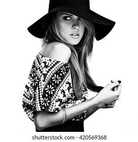 Beautiful young girl in a sweater with deer print and black hat. Black-white photo.