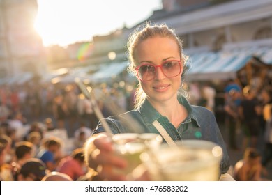 Beautiful young girl toasting outdoors on Open kitchen street food festival in Ljubljana, Slovenia. Popular summer urban tourist event in capital.