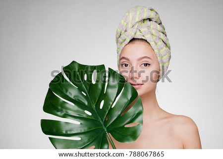 beautiful young girl with a towel on her head holds a green leaf, day spa