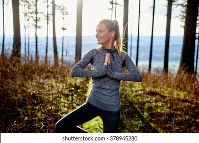 beautiful young girl walking in forest standing on log in yoga tree pose