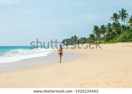 Beautiful young girl walks on a deserted tropical beach - paradise for vacation
