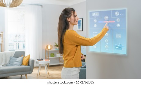 Beautiful Young Girl Walks Over to a Refrigerator. She is Changing Temperature on a Smart Fridge Screen at Home. Kitchen is Bright and Cozy.