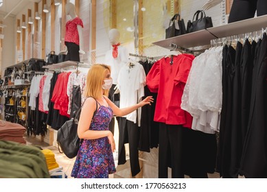 Beautiful Young Girl Wearing Disposable Face Mask Chooses Clothes At Clothes Shopping Store.Life With New Normal During Covid19 Outbreak.