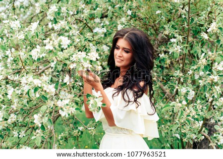 beautiful young girl in white dress in spring blossoming apple orchards