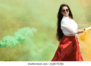 Beautiful young girl woman dance enjoy Multicolored smoke bombs cloud of dry color Holi powder colour gulal abeer event in spring break in the park Holi festival of color