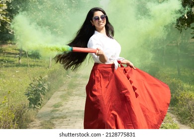Beautiful young girl woman dance with smoke bombs color smoke grenade in the park in spring break cloud of dry color Holi powder colour gulal abeer celebration of Festival of color holi