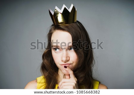 beautiful young girl in a yellow dress thought about something, on her head a golden crown