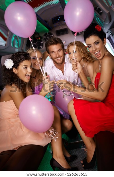 Beautiful young girls having party fun in limousine\
with handsome man.