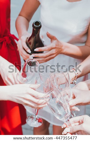 Beautiful young girls in red dresses are celebrating a bachelorette party and drink champagne