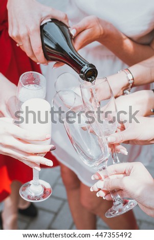 Beautiful young girls in red dresses are celebrating a bachelorette party and drink champagne