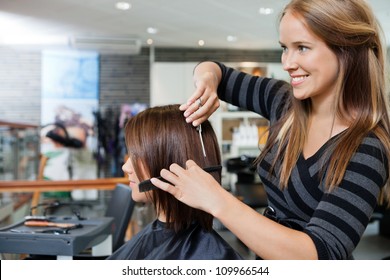 Beautiful young hairdresser giving a new haircut to female customer at parlor - Powered by Shutterstock