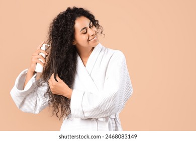 Beautiful young happy African-American woman with healthy curly hair and cosmetic product on beige background - Powered by Shutterstock